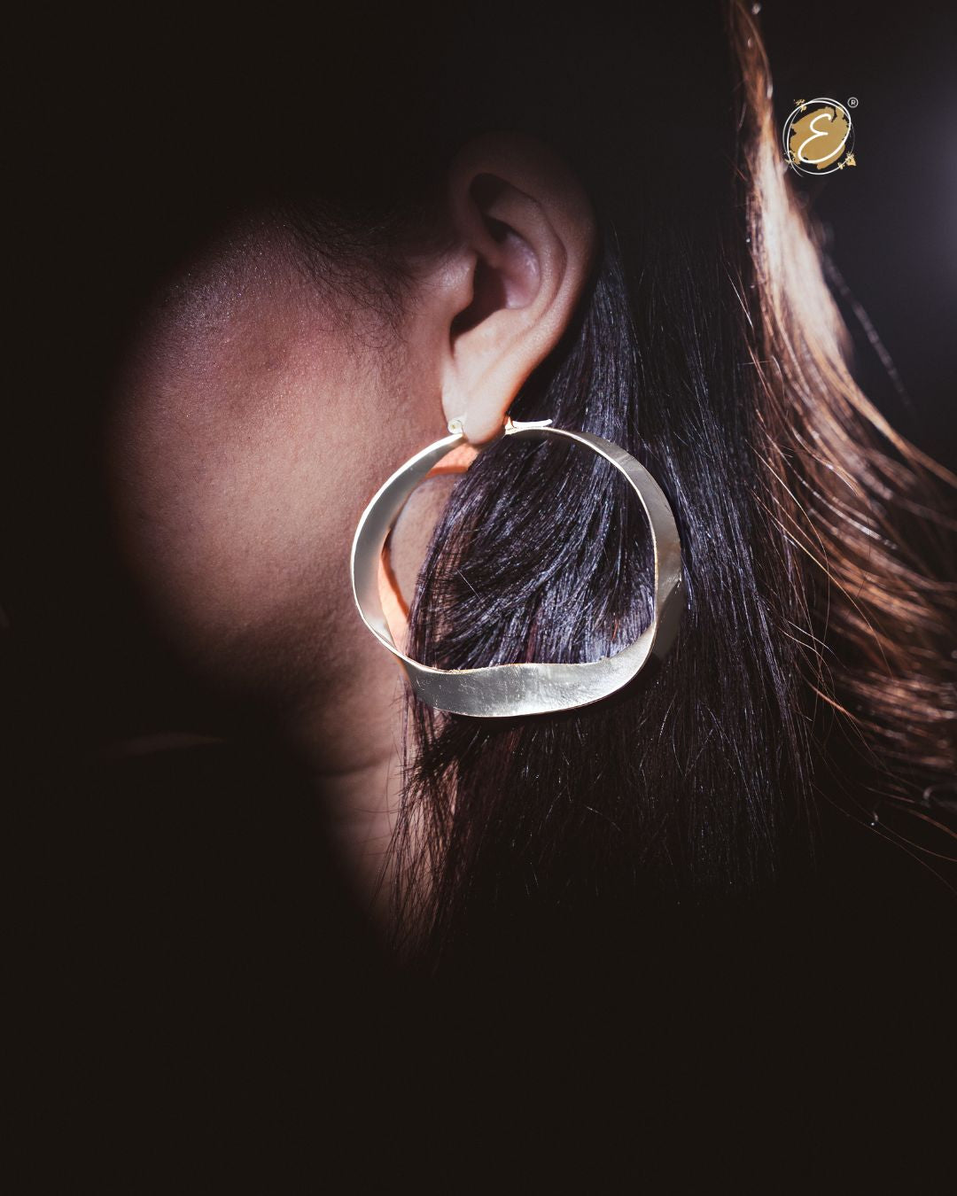 Sculptural silver hoop statement earrings with an elegant twisted design, handcrafted and silver-plated